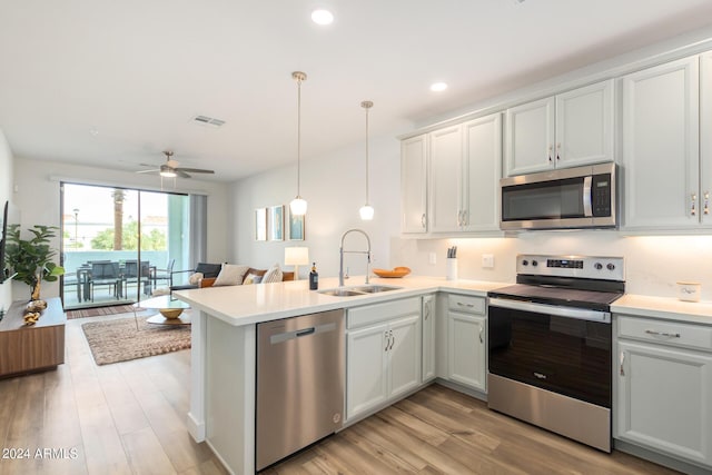 kitchen featuring visible vents, a peninsula, stainless steel appliances, light countertops, and a sink