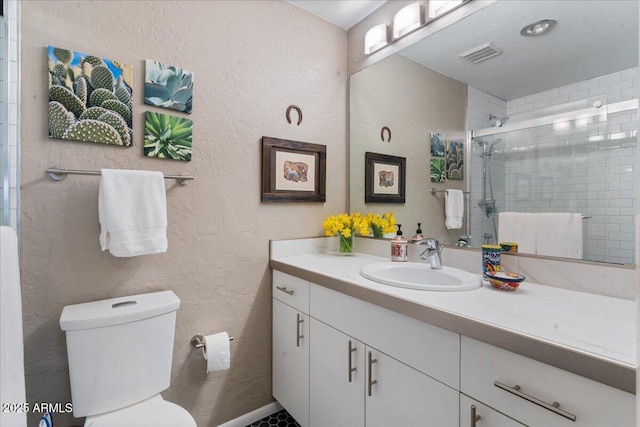 full bath with visible vents, toilet, a stall shower, a textured wall, and vanity