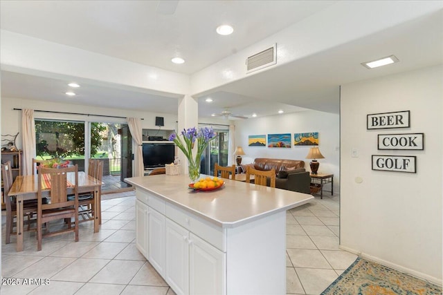 kitchen with light tile patterned floors, visible vents, light countertops, white cabinets, and open floor plan