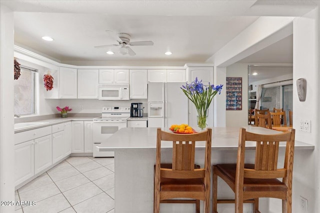 kitchen featuring white appliances, light tile patterned floors, a ceiling fan, a sink, and white cabinetry