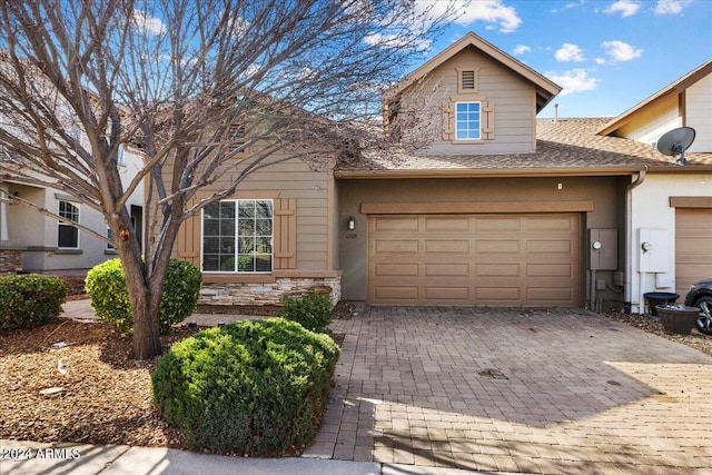 view of front of house featuring an attached garage, stone siding, decorative driveway, roof with shingles, and stucco siding