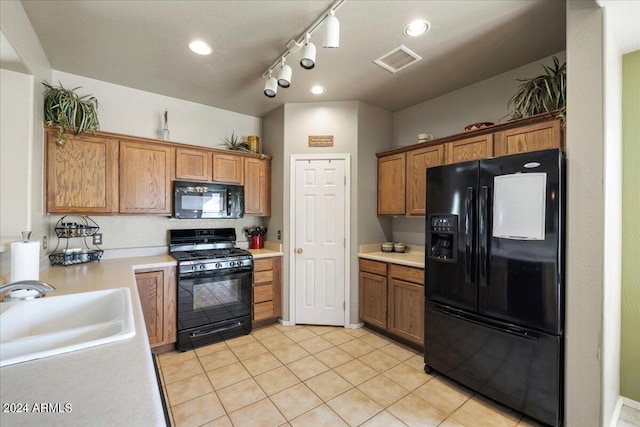 kitchen with visible vents, brown cabinetry, light countertops, black appliances, and a sink
