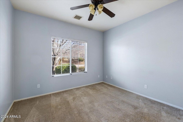 carpeted spare room featuring ceiling fan, visible vents, and baseboards