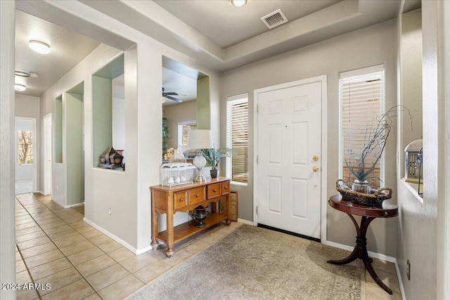 entrance foyer featuring baseboards, visible vents, ceiling fan, and light tile patterned flooring