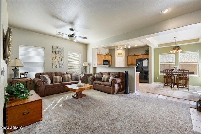 living room featuring light tile patterned floors, light colored carpet, visible vents, a ceiling fan, and baseboards