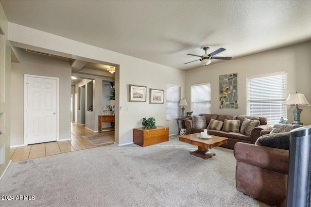 carpeted living room featuring ceiling fan, a textured ceiling, visible vents, baseboards, and tile patterned floors