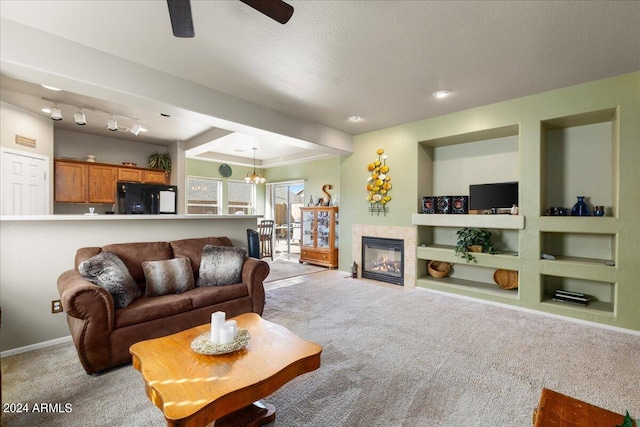 living room with built in shelves, a glass covered fireplace, light colored carpet, and a textured ceiling