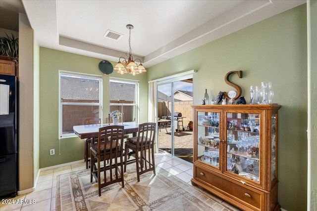 dining space with light tile patterned floors, visible vents, baseboards, a tray ceiling, and an inviting chandelier