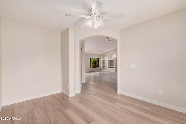3582 N 160th Ave, Goodyear, AZ 85395 - spare room featuring arched walkways, a ceiling fan, light wood finished floors, and baseboards