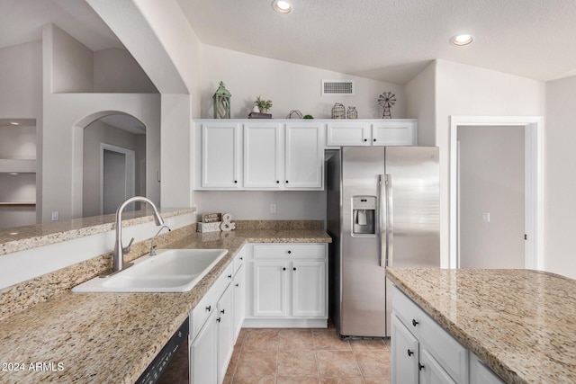 kitchen featuring stainless steel fridge, white cabinetry, sink, and vaulted ceiling