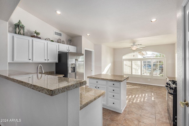 kitchen with white cabinetry, stainless steel appliances, light stone counters, kitchen peninsula, and vaulted ceiling