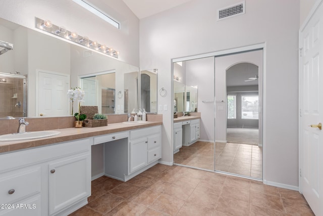 bathroom featuring ceiling fan, tile patterned flooring, a towering ceiling, vanity, and a shower with shower door