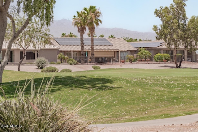 3582 N 160th Ave, Goodyear, AZ 85395 - view of front facade with a mountain view, roof mounted solar panels, a front lawn, stucco siding, and a tile roof