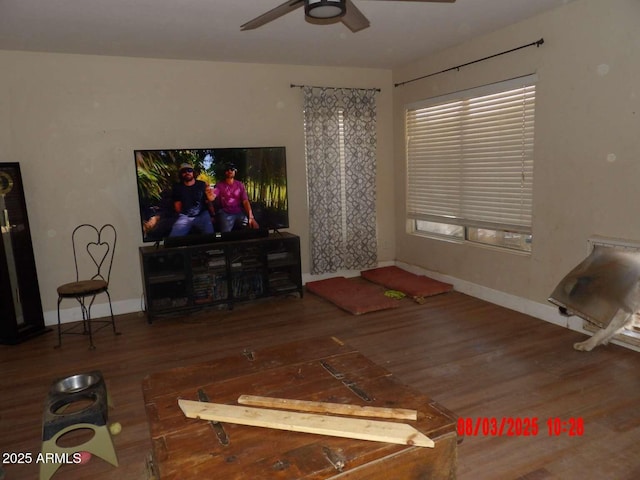 living area with baseboards, a ceiling fan, and wood finished floors