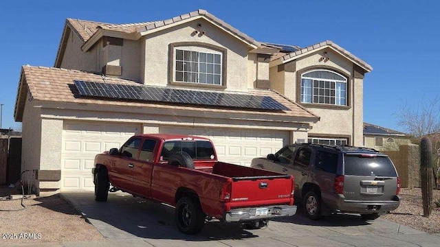 view of front of property featuring a garage, roof mounted solar panels, and stucco siding