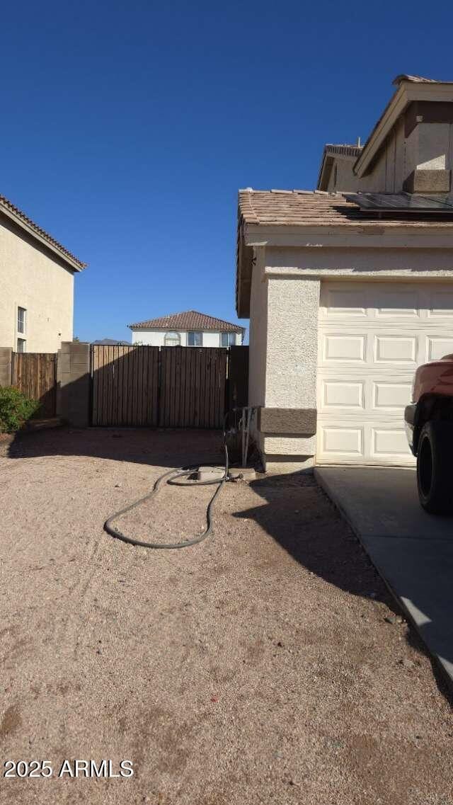 view of home's exterior featuring a gate, fence, driveway, stucco siding, and a garage