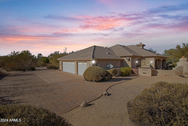 view of front of home with an attached garage, driveway, a tile roof, and stucco siding