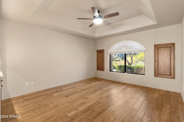 unfurnished room featuring ceiling fan, light hardwood / wood-style floors, and a raised ceiling