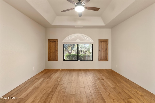 spare room with ceiling fan, light hardwood / wood-style floors, and a tray ceiling