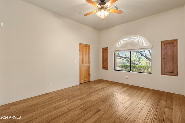 unfurnished room with a towering ceiling, light wood-type flooring, and ceiling fan