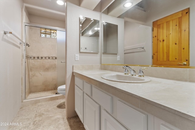 bathroom featuring a tile shower, vanity, and toilet