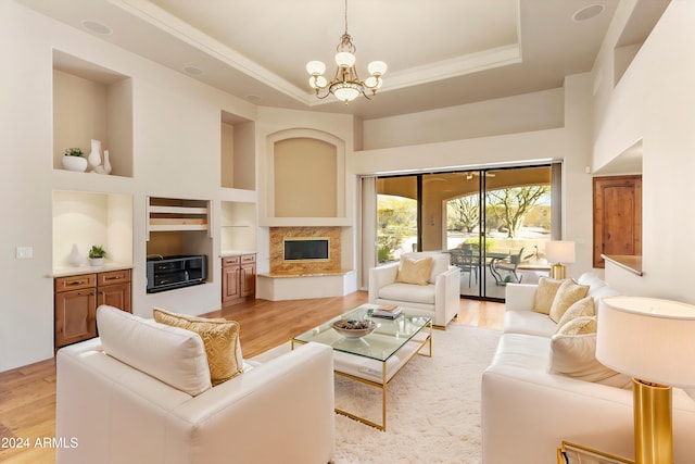 living room featuring light wood-style floors, a high end fireplace, a raised ceiling, and built in shelves