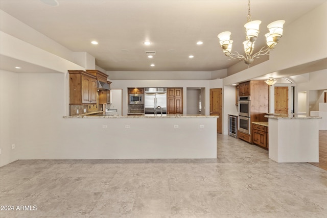 kitchen featuring hanging light fixtures, built in appliances, light stone countertops, kitchen peninsula, and a chandelier