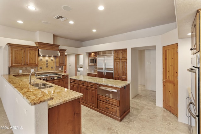 kitchen featuring light stone countertops, sink, tasteful backsplash, kitchen peninsula, and built in appliances