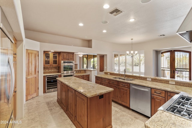 kitchen with sink, beverage cooler, decorative light fixtures, a kitchen island, and appliances with stainless steel finishes