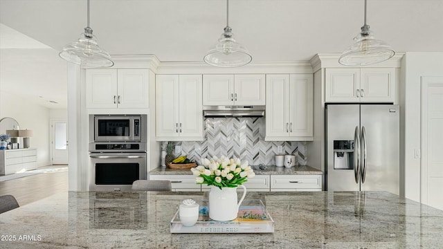 kitchen featuring stainless steel appliances, light stone counters, and decorative light fixtures