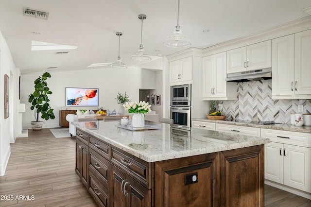 kitchen featuring light hardwood / wood-style flooring, hanging light fixtures, stainless steel appliances, dark brown cabinetry, and decorative backsplash