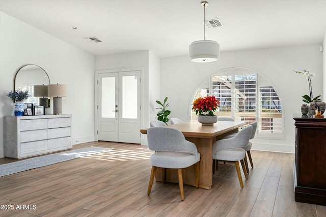 dining space with french doors and light wood-type flooring