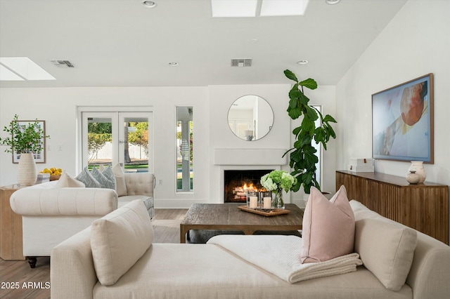 living room with french doors, a skylight, and light wood-type flooring