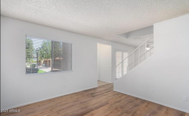 3511 E Baseline Rd Unit 1235, Phoenix, AZ 85042 - spare room with wood finished floors, a textured ceiling, baseboards, and stairs
