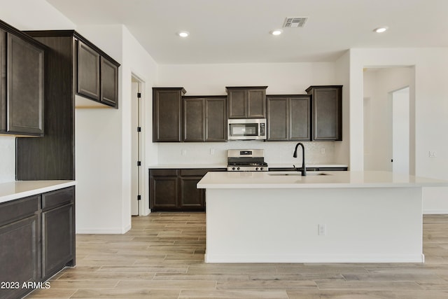 kitchen with sink, light hardwood / wood-style flooring, an island with sink, and appliances with stainless steel finishes