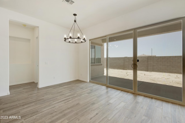 unfurnished dining area featuring light hardwood / wood-style flooring and a notable chandelier