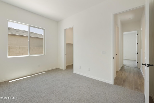 unfurnished bedroom featuring light colored carpet and a spacious closet