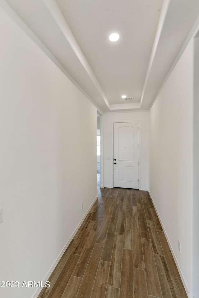 corridor featuring a tray ceiling and dark hardwood / wood-style floors