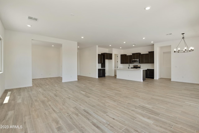 unfurnished living room with a notable chandelier and light hardwood / wood-style flooring