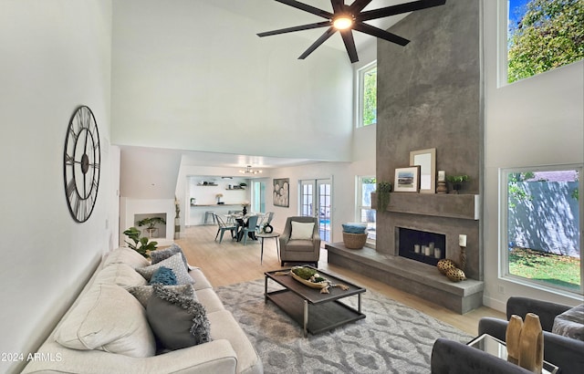 living room featuring a high ceiling, ceiling fan, a wealth of natural light, and wood-type flooring