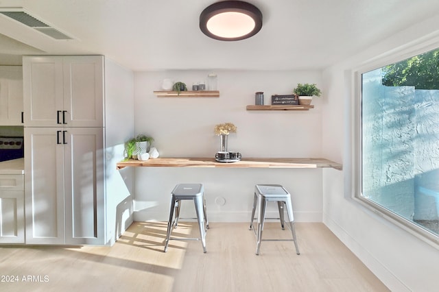 interior space featuring plenty of natural light, light wood-type flooring, white cabinets, and built in desk