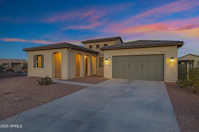 prairie-style house with driveway, fence, stucco siding, and a garage