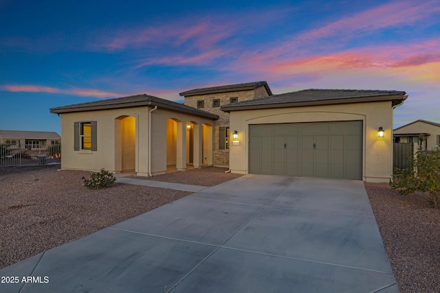 view of front facade featuring a garage, driveway, fence, and stucco siding