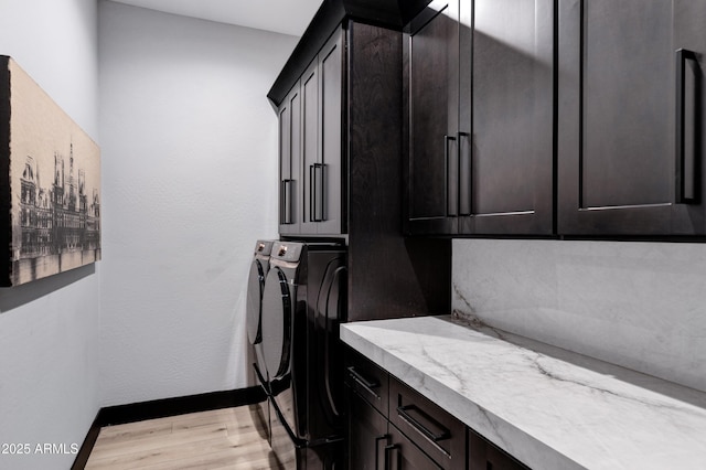 washroom featuring light wood-style floors, baseboards, cabinet space, and independent washer and dryer
