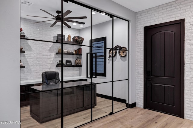 office area featuring brick wall, visible vents, ceiling fan, and wood finished floors