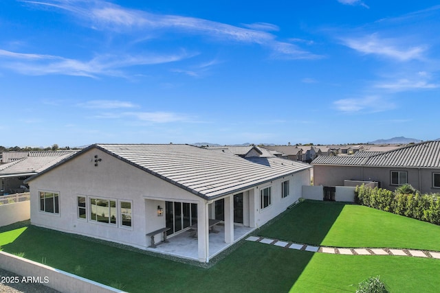 back of house with a patio, a yard, a tiled roof, stucco siding, and fence
