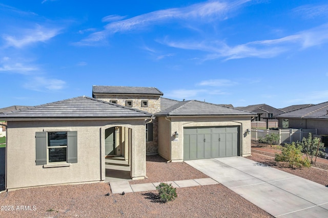 view of front of home featuring stucco siding, fence, a garage, a tile roof, and concrete driveway