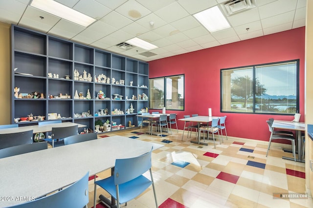 office area with tile patterned floors, visible vents, and a drop ceiling