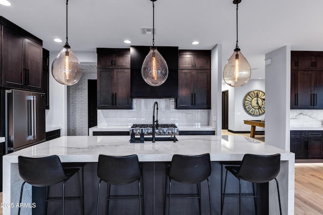 kitchen featuring tasteful backsplash, visible vents, recessed lighting, light wood finished floors, and extractor fan