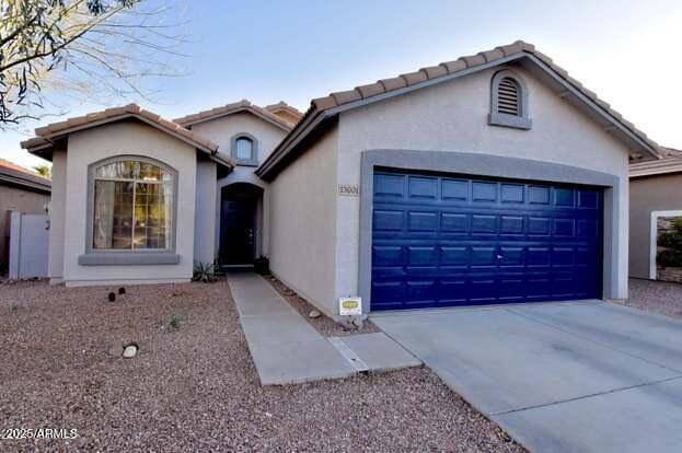 view of front facade with concrete driveway, an attached garage, a tile roof, and stucco siding